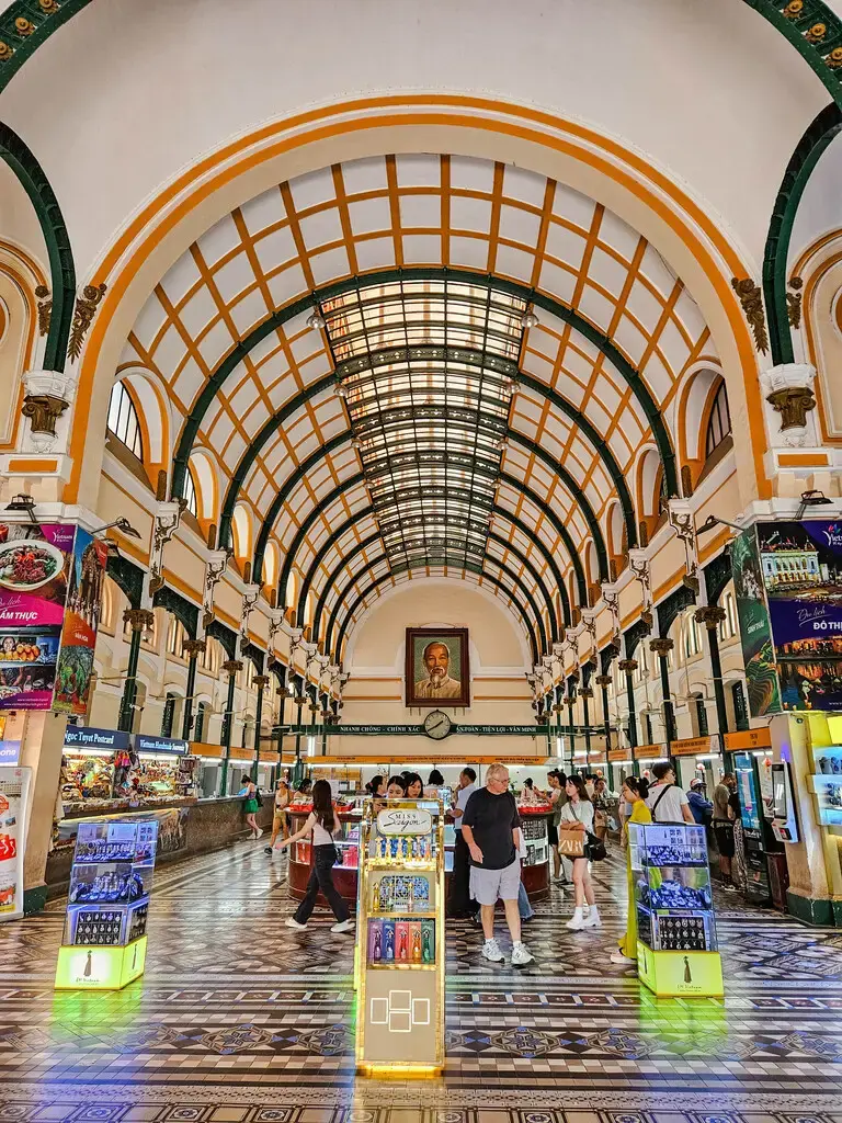 2025胡志明市旅遊指南|從行前準備到在地美食景點,一篇搞懂自由行大小事 胡志明市中央郵局的內部大廳,可見拱形天花板、老式電話亭和遊客。 (Interior hall of Saigon Central Post Office in Ho Chi Minh City, showing the arched ceiling, old phone booths, and visitors.)