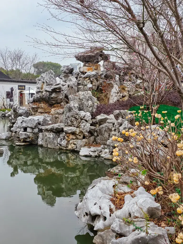 2026 蘇州旅遊攻略|5日遊深度自由行:避開人潮的園林路線、美食、住宿、交通一次搞懂 蘇州景點推薦:唐寅故居入口東池,錯落有致的湖石假山與池水倒影,展現典型蘇州園林造景美學,適合規畫進蘇州自由行攝影行程中。