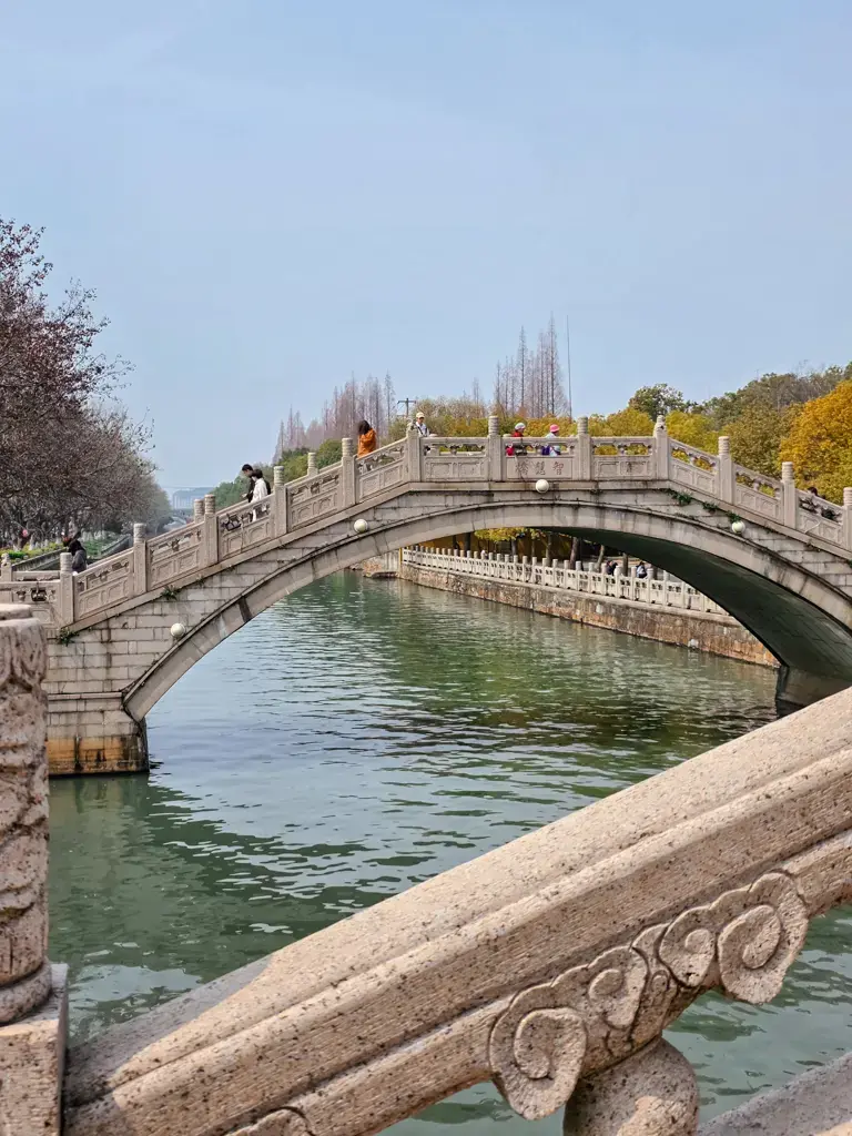 2026 蘇州旅遊攻略|5日遊深度自由行:避開人潮的園林路線、美食、住宿、交通一次搞懂 蘇州西園寺「智慧橋」石拱橋全景,護城河畔的古風建築與江南水鄉垂柳景觀