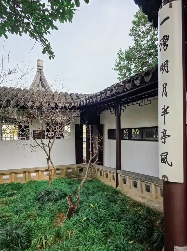 2026 蘇州旅遊攻略|5日遊深度自由行:避開人潮的園林路線、美食、住宿、交通一次搞懂 蘇州景點:滄浪亭的古典園林長廊,柱上題有「一灣明月半亭風」對聯,背景為精緻的蘇式漏窗與白牆黛瓦景觀。