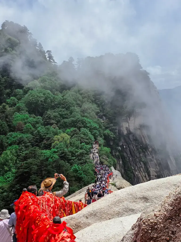 中國五嶽之一的險峻山徑的震撼俯瞰視角,雲霧籠罩著絕壁與華山西峰懸崖步道