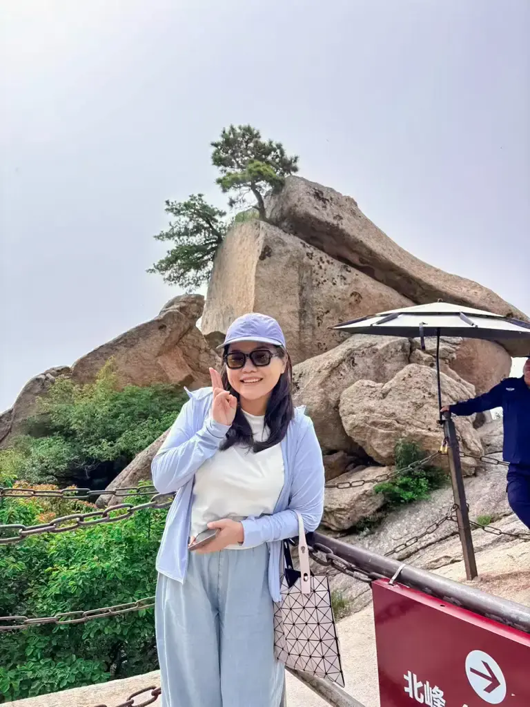 遊客在華山北峰地標前合影,後方為雲台峰的經典奇岩景觀
