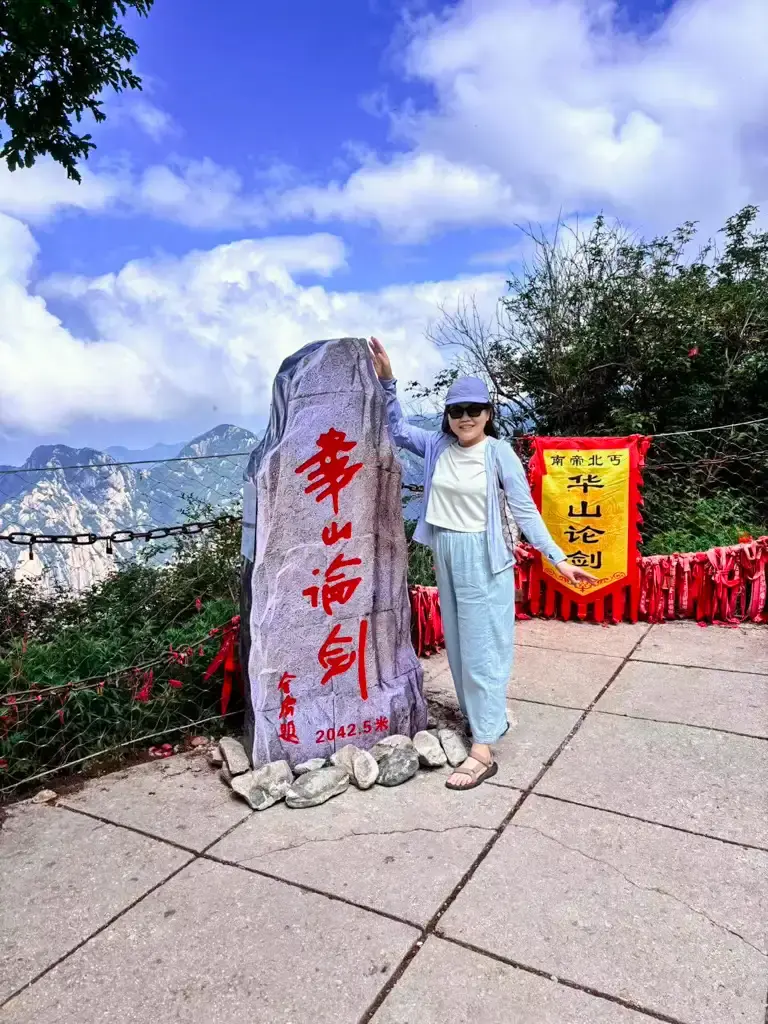 遊客在陝西華山著名的「華山論劍」石碑前合影,後方是壯闊的山脈景觀