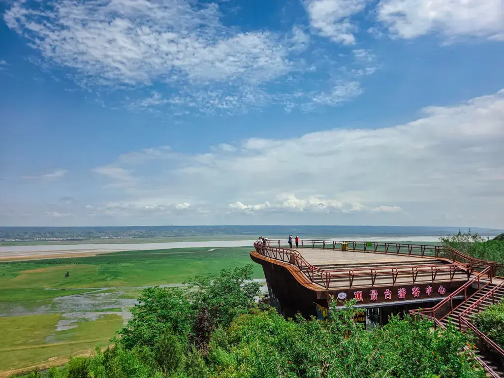 陝西景點:韓城黃河觀景台(沿黃公路姚家莊段)私房景點實拍:一座標示有「觀景台遊客中心」的大船造型木棧道平台,遠眺黃河衝出晉陝大峽谷後,與遼闊的綠色沖積大草原、開闊江景交會的壯麗風光。
