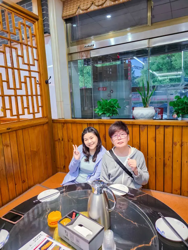 山西河津自駕遊美食推薦:旅人在當地熱門餐廳「晉運特色麵」的木質調半開放式包廂大圓桌前合影留念,展現道地的地方飲食體驗與歡樂的旅途氛圍。