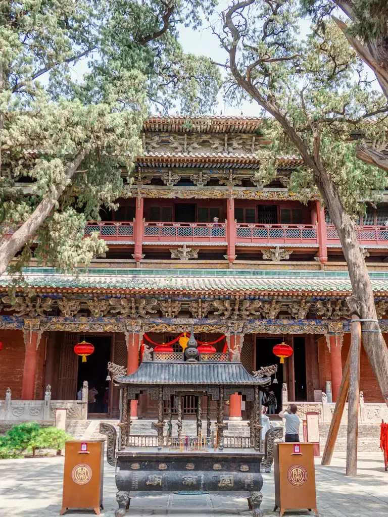 山西運城解州關帝廟內的「春秋樓」古建築全景,展現高大宏偉且罕見的懸梁吊柱木構工藝,前方廣場設有黑色大香爐,周邊古樹環繞,呈現武廟名樓的莊嚴氣場。