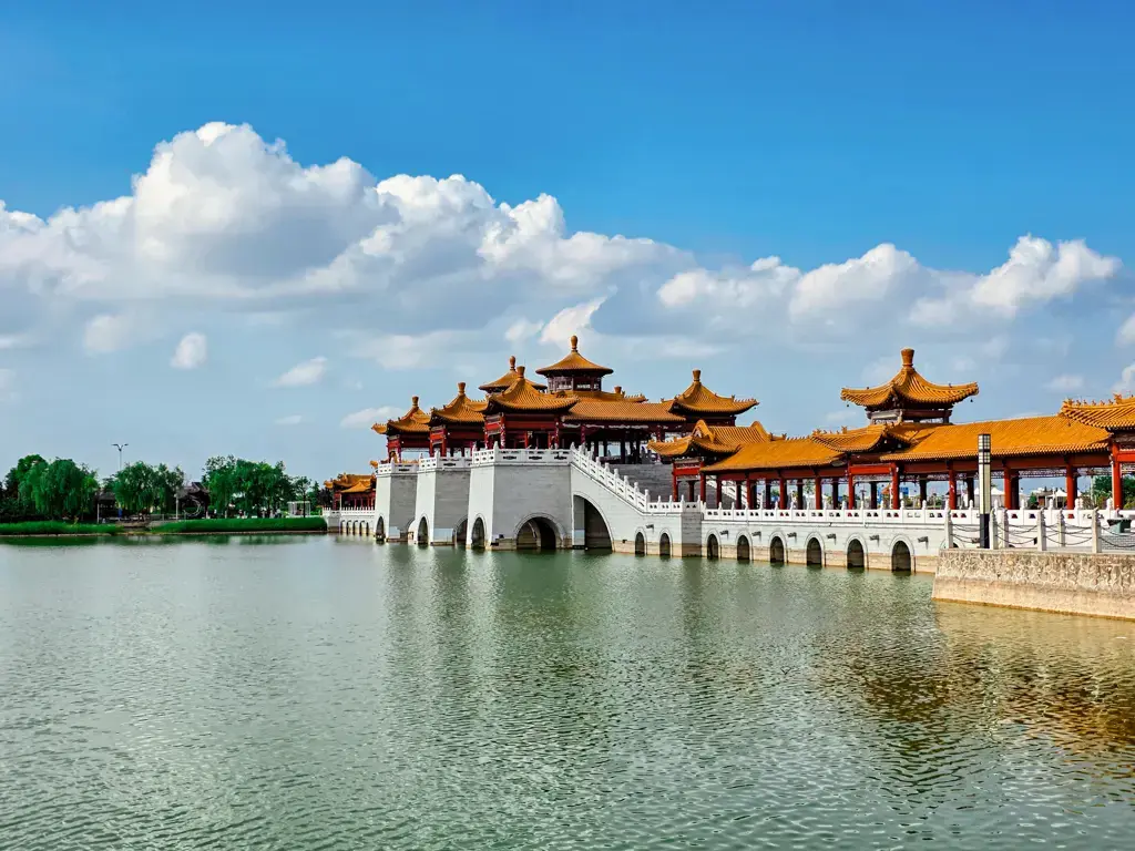 陝西大荔沙苑水庫(當地人暱稱南湖)的唯美風光,一座宏偉的白色多孔仿古廊橋橫跨於清澈的綠色湖面上,黃瓦紅柱的傳統中式閣樓在藍天白雲倒映下顯得古意盎然。