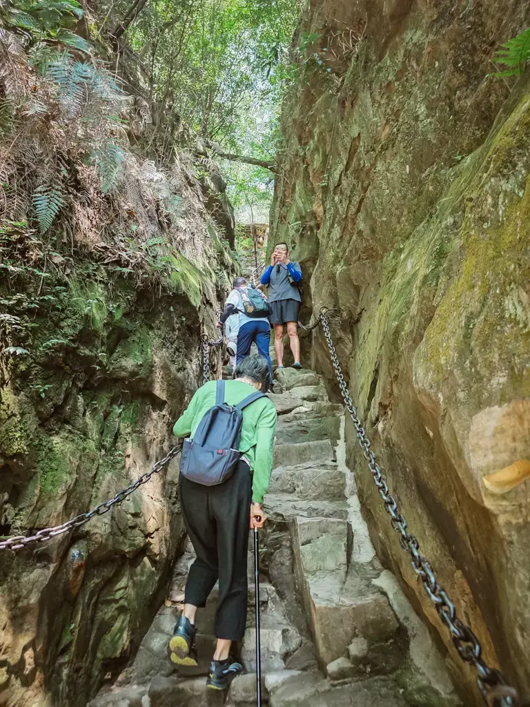 媽媽手扶兩側鐵鍊手扶梯攀爬楊家界烏龍寨陡峭石階