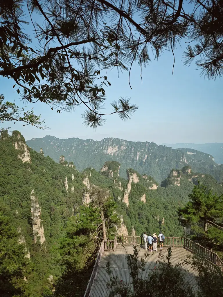 張家界天子山木造觀景平台,遊客站在欄杆旁欣賞遠方層疊山峰與石柱景觀