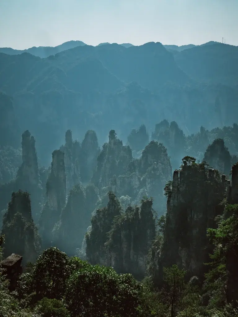 張家界天子山御筆峰景觀,數座細長石柱矗立在群山之間,遠方山巒呈現朦朧的藍灰色層次