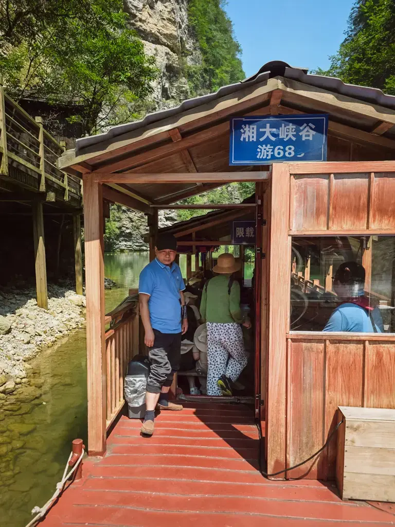 張家界大峽谷彩虹湖碼頭，標有「湘大峽谷游68」的木造遊船與準備上船的遊客